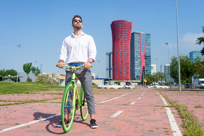 Young bearded man with sunglasses standing with bike outdoors