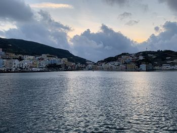 Town by sea against sky during sunset in city