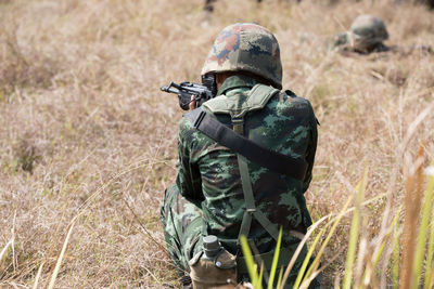 Army soldier shooting with rifle on field