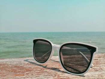 Close-up of sunglasses on sea against clear sky