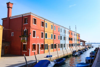 Buildings by canal against clear blue sky