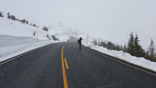 Man standing on mountain road during snowfall