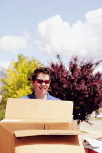 Smiling mid adult lesbian woman carrying cardboard box