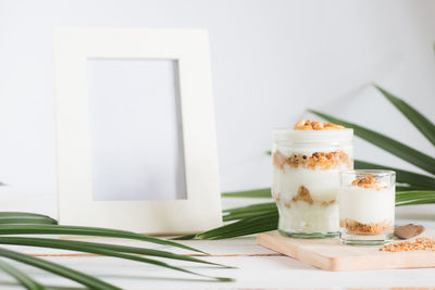 Close-up of dessert in glass by empty picture frame on table