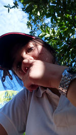 Close-up portrait of young woman against trees