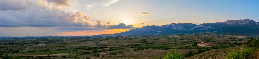 Panoramic view of agricultural field against sky during sunset