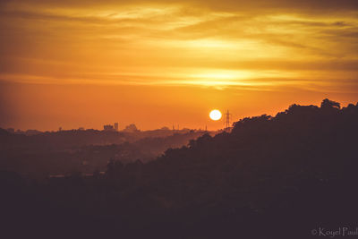 Silhouette landscape against dramatic sky during sunset