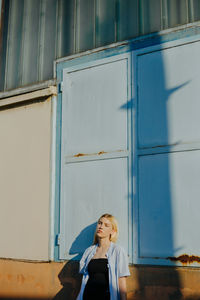 Woman looking away while standing against building