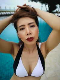 Portrait of woman wearing bikini while standing against swimming pool