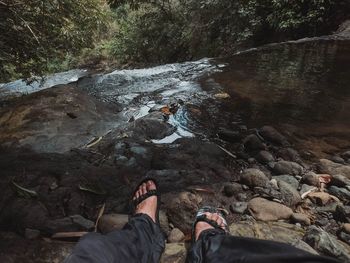 Low section of woman standing on rock by river