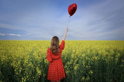 Rear view of woman standing on field against sky