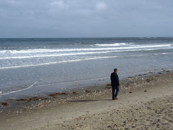 Rear view of man on beach against sky