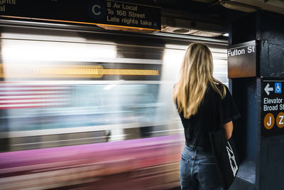 Beautiful young girl waiting in metro station with train movement