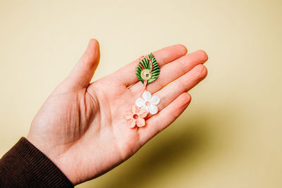 The hand of a woman holds in her palm one beautiful martisor of flowers, a petal and a smiley face 