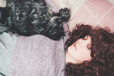 Woman with dog lying on bed at home