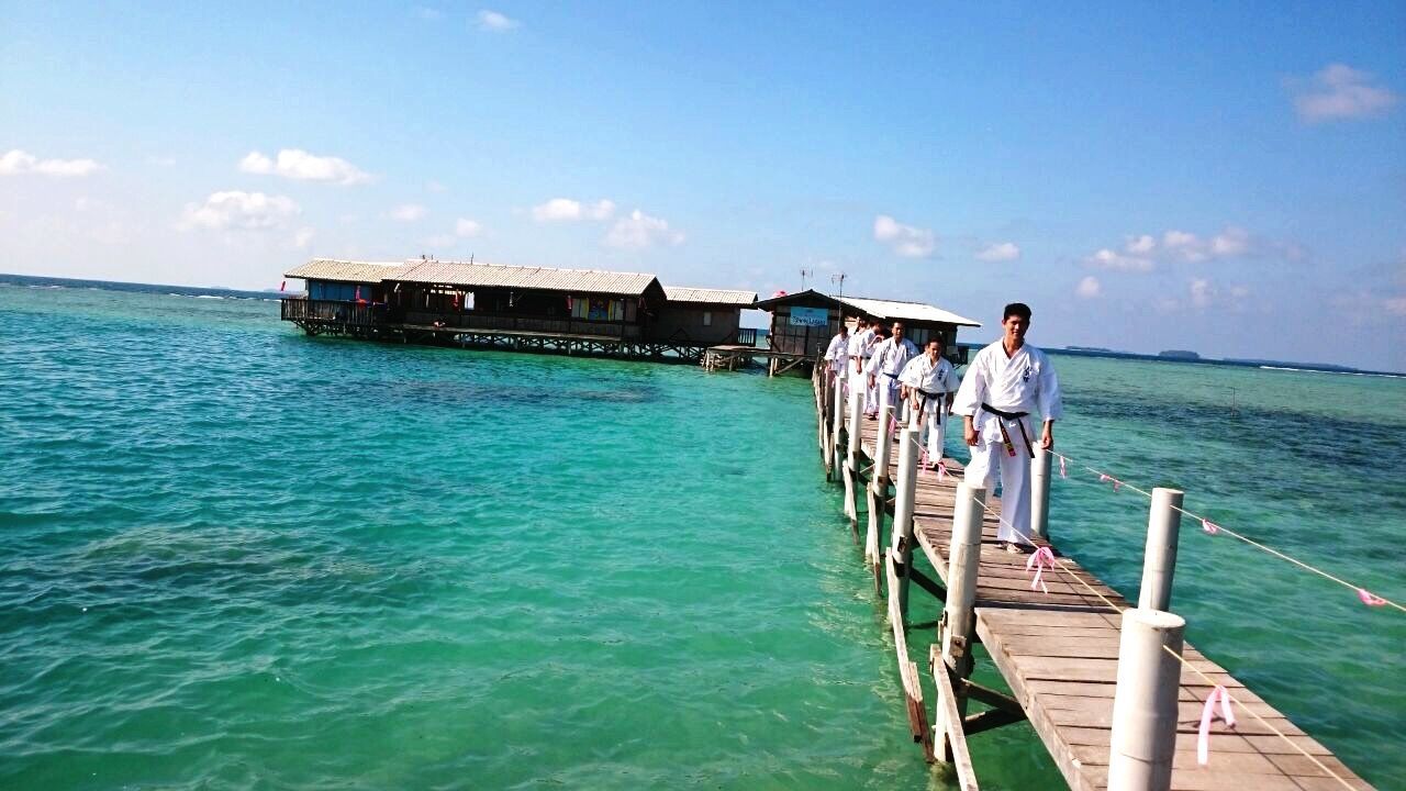 PEOPLE STANDING ON BOAT AGAINST SEA