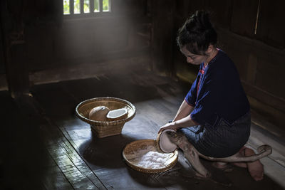 Side view of woman grating coconut at home