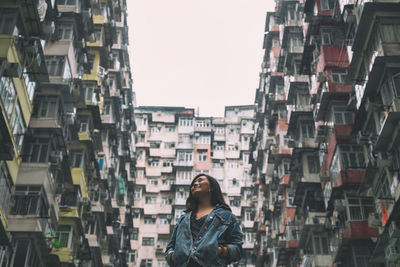 Smiling woman looking up against building in city