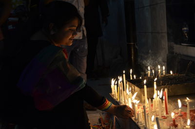 Side view of woman standing against illuminated fire