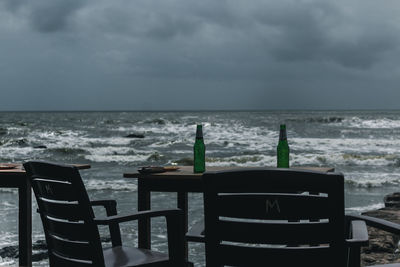 Chairs and table at beach against sky