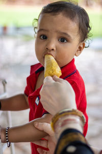 Cute toddler baby boy eating ice creme in casual appearance at outdoor