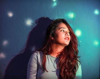 Close-up of woman looking away sitting by wall