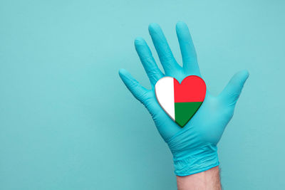 Close-up of hand holding heart shape against blue background