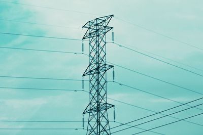 Low angle view of electricity pylon against blue sky