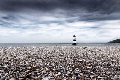 Lighthouse on beach against sky