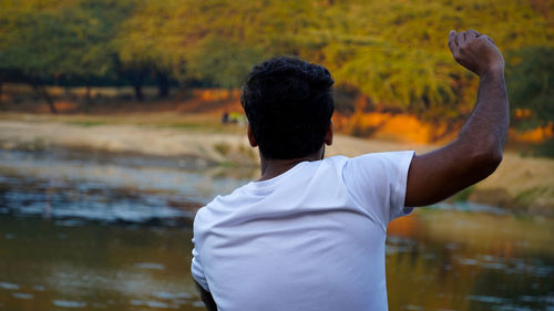 Rear view of woman standing by lake