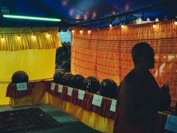 Rear view of man standing in illuminated market