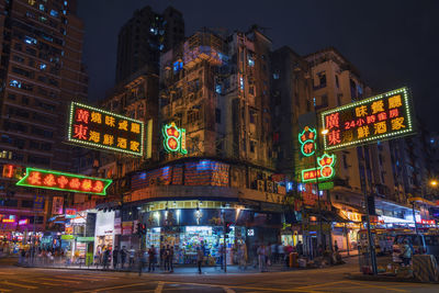 City street by illuminated buildings at night