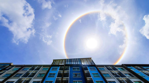 Low angle view of rainbow over building against sky