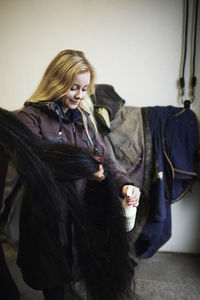 Young woman grooming horse after riding in stable