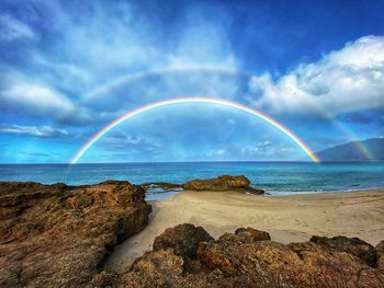 Scenic view of rainbow over sea against sky