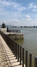 Wooden posts in sea against sky