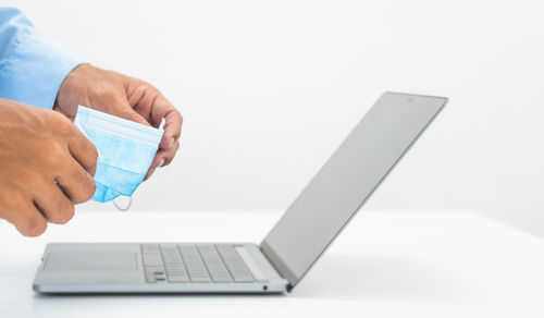 Close-up of hand holding smart phone over white background