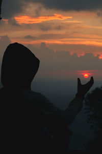 Rear view of silhouette man against orange sky