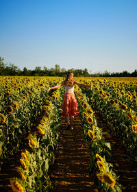 Rear view of woman walking on field against clear sky