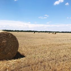 Hay bales on field against sky