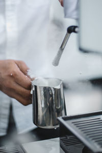 Midsection of man making coffee in cafe