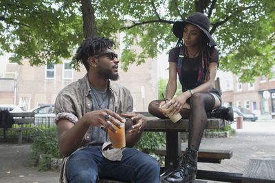 A young man and a young woman at a picnic table with iced coffee.