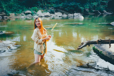 Full length of smiling young woman in lake
