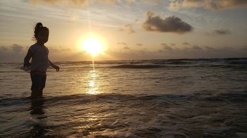 Boy on beach against sky during sunset