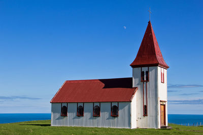 Church by sea against clear blue sky