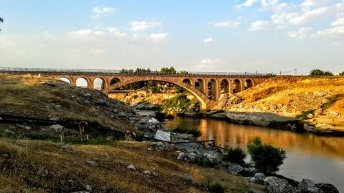 Arch bridge over river against sky