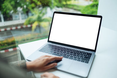 A hand using and touching on laptop computer touchpad with blank white desktop screen