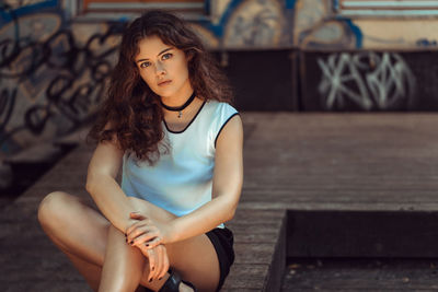 Portrait of beautiful young woman sitting on boardwalk