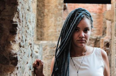 Portrait of woman with dreadlocks against wall
