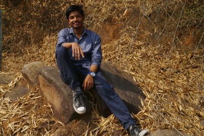 Portrait of young man sitting on field